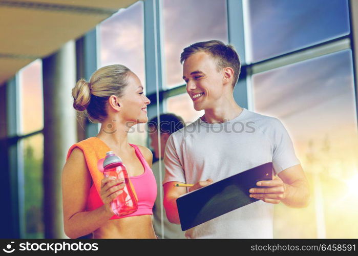 fitness, sport, exercising and diet concept - smiling young woman with personal trainer after training in gym. smiling young woman with personal trainer in gym