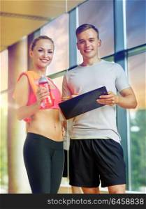 fitness, sport, exercising and diet concept - smiling young woman with personal trainer after training in gym. smiling young woman with personal trainer in gym