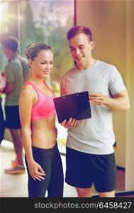 fitness, sport, exercising and diet concept - smiling young woman with personal trainer in gym. smiling young woman with personal trainer in gym
