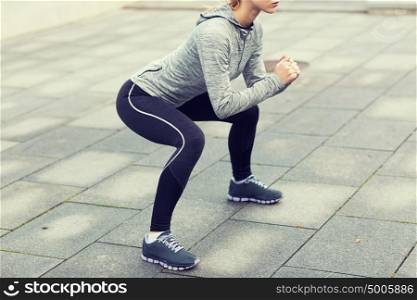 fitness, sport, exercising and healthy lifestyle concept - close up of woman doing squats outdoors. close up of woman doing squats outdoors