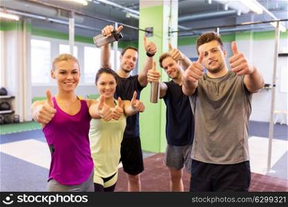 fitness, sport, exercising and healthy lifestyle concept - group of happy people in gym showing thumbs up. group of happy friends in gym showing thumbs up