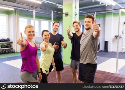 fitness, sport, exercising and healthy lifestyle concept - group of happy people in gym showing thumbs up. group of happy friends in gym showing thumbs up