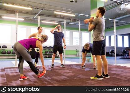 fitness, sport, exercising and healthy lifestyle concept - group of happy people stretching in gym. group of happy friends stretching in gym