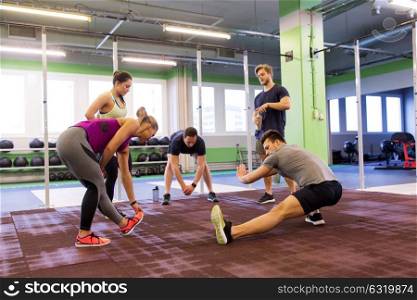 fitness, sport, exercising and healthy lifestyle concept - group of happy people stretching in gym. group of happy friends stretching in gym