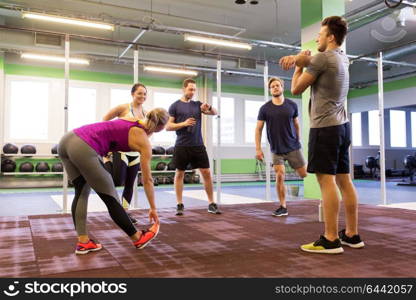 fitness, sport, exercising and healthy lifestyle concept - group of happy people stretching in gym. group of happy friends stretching in gym