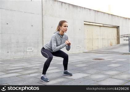 fitness, sport, exercising and healthy lifestyle concept - happy woman doing squats outdoors