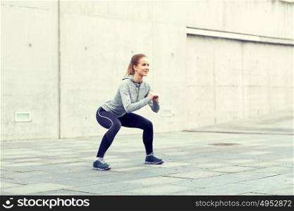 fitness, sport, exercising and healthy lifestyle concept - happy woman doing squats outdoors. happy woman doing squats and exercising outdoors