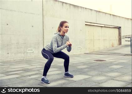 fitness, sport, exercising and healthy lifestyle concept - happy woman doing squats outdoors. happy woman doing squats and exercising outdoors. happy woman doing squats and exercising outdoors