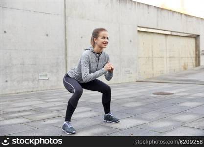 fitness, sport, exercising and healthy lifestyle concept - happy woman doing squats outdoors
