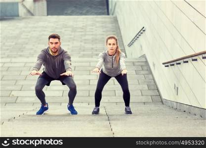 fitness, sport, exercising and healthy lifestyle concept - man and woman doing squats outdoors. couple doing squats and exercising outdoors