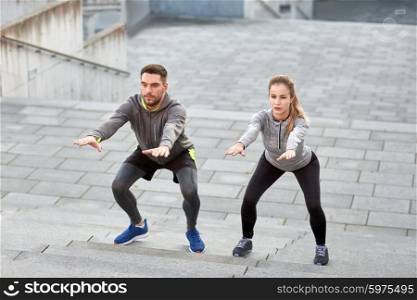 fitness, sport, exercising and healthy lifestyle concept - man and woman doing squats outdoors