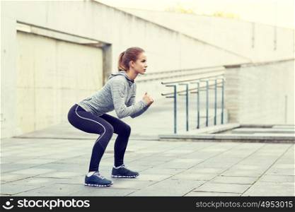fitness, sport, exercising and healthy lifestyle concept - woman doing squats outdoors. woman doing squats and exercising outdoors