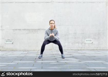 fitness, sport, exercising and healthy lifestyle concept - woman doing squats outdoors