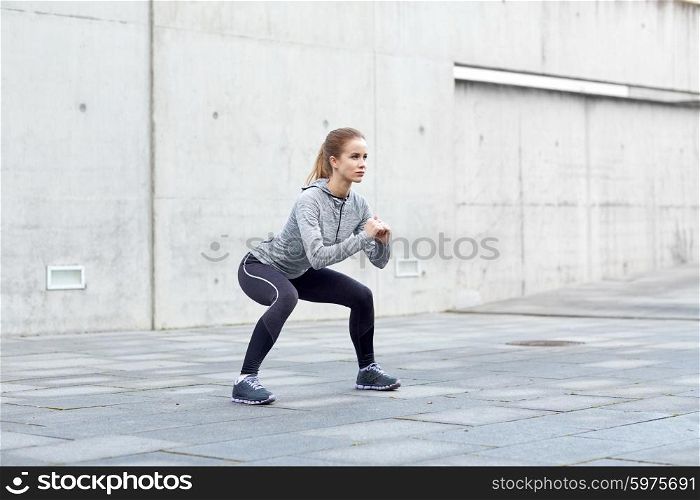 fitness, sport, exercising and healthy lifestyle concept - woman doing squats outdoors