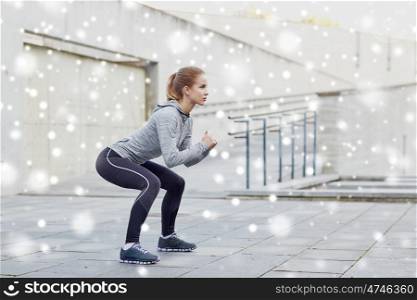 fitness, sport, exercising and healthy lifestyle concept - woman doing squats outdoors over snow