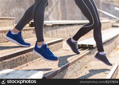 fitness, sport, exercising and lifestyle concept - close up of couple or friends running downstairs on stadium