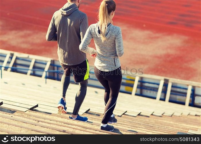 fitness, sport, exercising and lifestyle concept - couple running downstairs on stadium. couple running downstairs on stadium