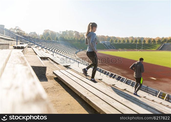 fitness, sport, exercising and lifestyle concept - couple running downstairs on stadium