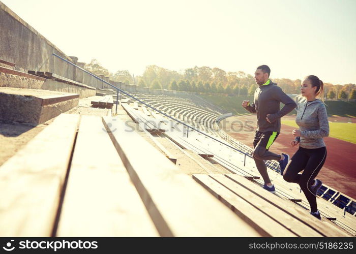 fitness, sport, exercising and lifestyle concept - couple running upstairs on stadium. couple running upstairs on stadium