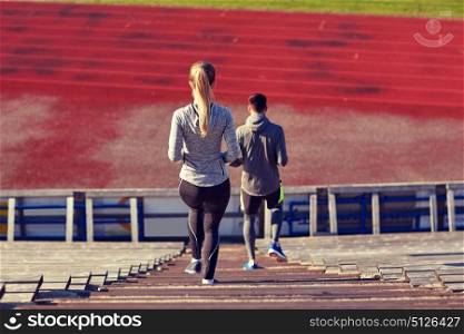 fitness, sport, exercising and lifestyle concept - couple walking downstairs on stadium. couple walking downstairs on stadium