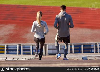 fitness, sport, exercising and lifestyle concept - couple walking downstairs on stadium