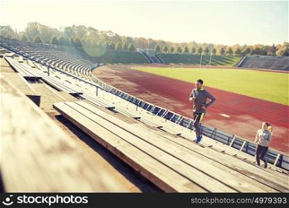 fitness, sport, exercising and lifestyle concept - happy couple running upstairs on stadium. happy couple running upstairs on stadium