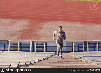 fitness, sport, exercising and lifestyle concept - man running upstairs on stadium