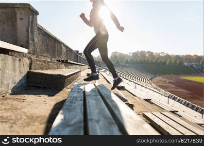fitness, sport, exercising and people concept - close up of young woman running upstairs on stadium