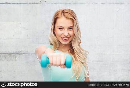 fitness, sport, exercising and people concept - smiling beautiful sporty woman with dumbbell over gray concrete wall background