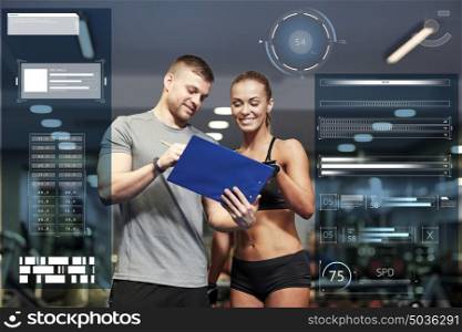 fitness, sport, exercising and people concept - smiling young woman and personal trainer with clipboard writing exercise plan in gym over virtual charts. smiling young woman with personal trainer in gym
