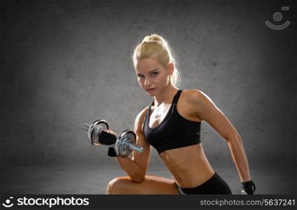 fitness, sport, exercising and people concept - sporty woman with heavy steel dumbbells over concrete wall background