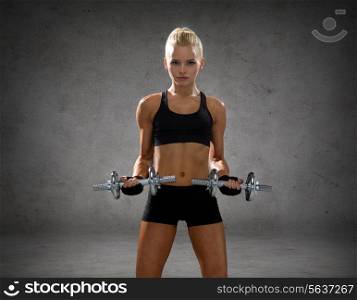 fitness, sport, exercising and people concept - sporty woman with heavy steel dumbbells over concrete wall background