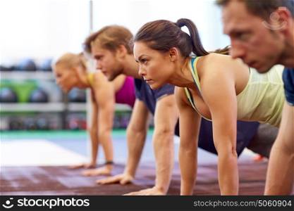 fitness, sport, exercising and people concept - woman doing straight arm plank at group training in gym. group of people doing straight arm plank in gym