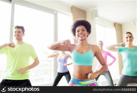 fitness, sport, exercising and training concept - group of smiling people with coach dancing or working out fighting stance in gym