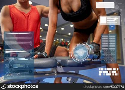 fitness, sport, exercising, bodybuilding and people concept - close up of young woman and personal trainer with dumbbell flexing muscles in gym over virtual charts. young couple with dumbbell flexing muscles in gym