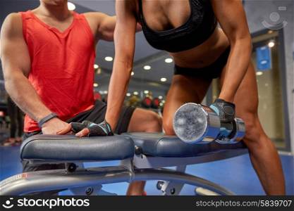 fitness, sport, exercising, bodybuilding and weightlifting concept - close up of young woman and personal trainer with dumbbell flexing muscles in gym