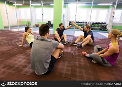 fitness, sport, exercising, gesture and healthy lifestyle concept - group of happy people resting and making high five in gym. group of happy friends making high five in gym