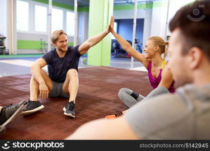 fitness, sport, exercising, gesture and healthy lifestyle concept - group of happy people resting and making high five in gym. group of happy friends making high five in gym