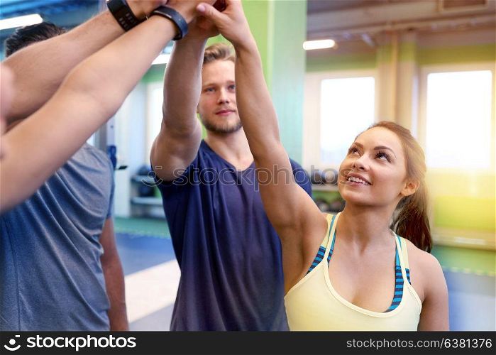 fitness, sport, exercising, gesture and people concept - group of happy friends making high five in gym. group of happy friends making high five in gym