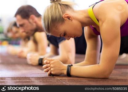 fitness, sport, exercising, people and healthy lifestyle concept - close up of woman with heart-rate tracker at group training doing plank exercise in gym. close up of woman at training doing plank in gym. close up of woman at training doing plank in gym
