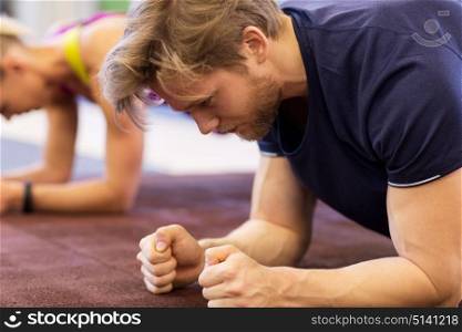 fitness, sport, exercising, people and healthy lifestyle concept - close up of man at group training doing plank exercise in gym. close up of man at training doing plank in gym