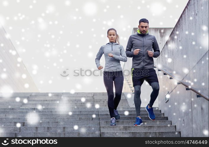 fitness, sport, exercising, people and healthy lifestyle concept - couple of sportsmen walking downstairs over snow