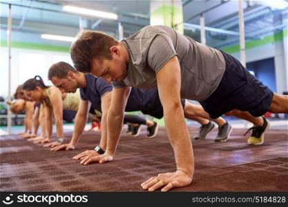 fitness, sport, exercising, training and healthy lifestyle concept - group of people doing straight arm plank in gym. group of people doing straight arm plank in gym