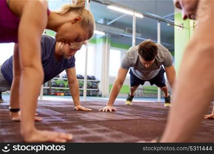 fitness, sport, exercising, training and healthy lifestyle concept - group of people doing straight arm plank in gym. group of people doing straight arm plank in gym