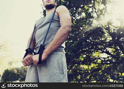 fitness, sport, exercising, training and lifestyle concept - close up of young man exercising with expander in summer park