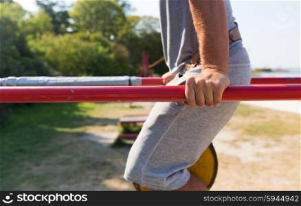 fitness, sport, exercising, training and lifestyle concept - close up of young man doing triceps dip with weight belt on parallel bars outdoors