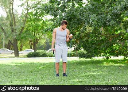 fitness, sport, exercising, training and lifestyle concept - young man exercising with expander in summer park