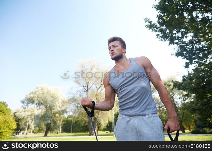 fitness, sport, exercising, training and lifestyle concept - young man exercising with expander in summer park