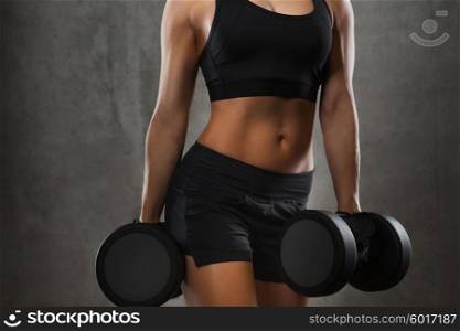 fitness, sport, exercising, training and people concept - close up of young woman flexing muscles with dumbbells in gym