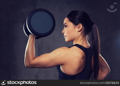 fitness, sport, exercising, training and people concept - young woman flexing muscles with dumbbells in gym. young woman flexing muscles with dumbbells in gym